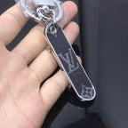 Black monogram skateboard keychain held in an open palm