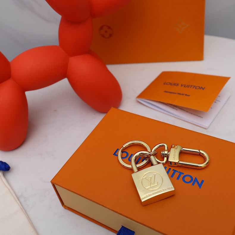 Gold-tone padlock charm and keyring laid flat on packaging