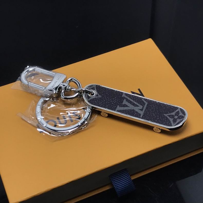 Black monogram skateboard keychain displayed on orange packaging