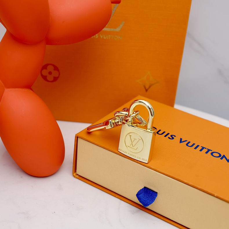Gold-tone padlock keychain resting upright on an orange box