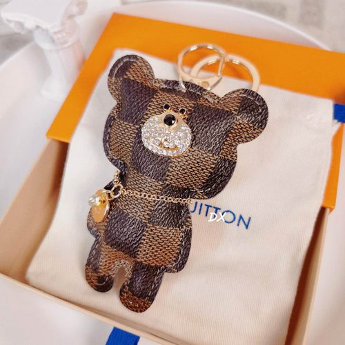 Checkered bear charm resting on a pouch inside a box