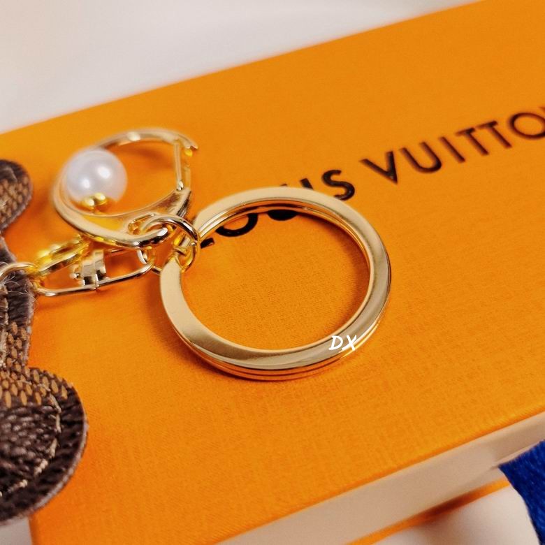 Close-up of gold-tone ring and pearl detail on bear keychain