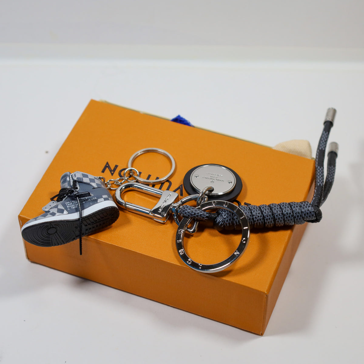 Black sneaker keychain with sole facing outward beside its cord