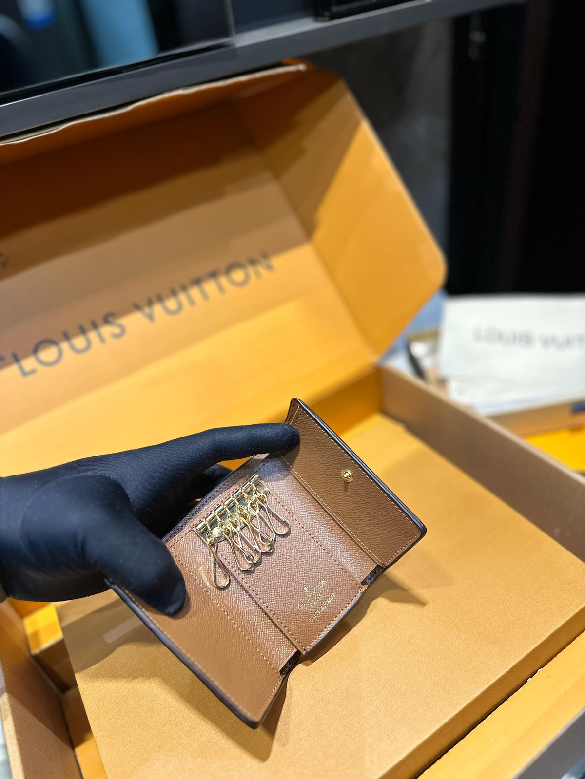 Opened six-key holder showing tan lining and metal hooks
