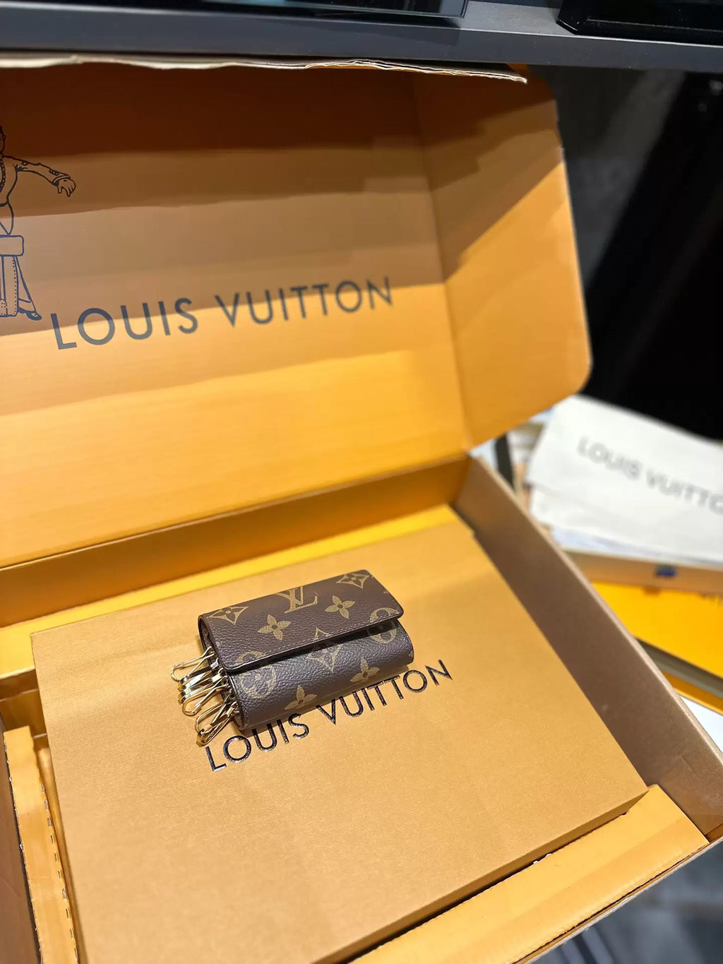 Closed brown monogram six-key holder displayed inside a box