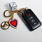 White cube keychain and red heart charm beside a car key
